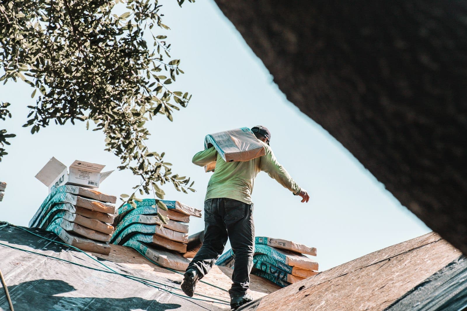 Roofer carrying shingles across a residential roof