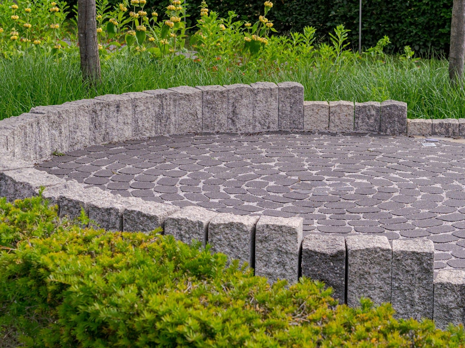 Circular paver patio bordered by a low stone wall