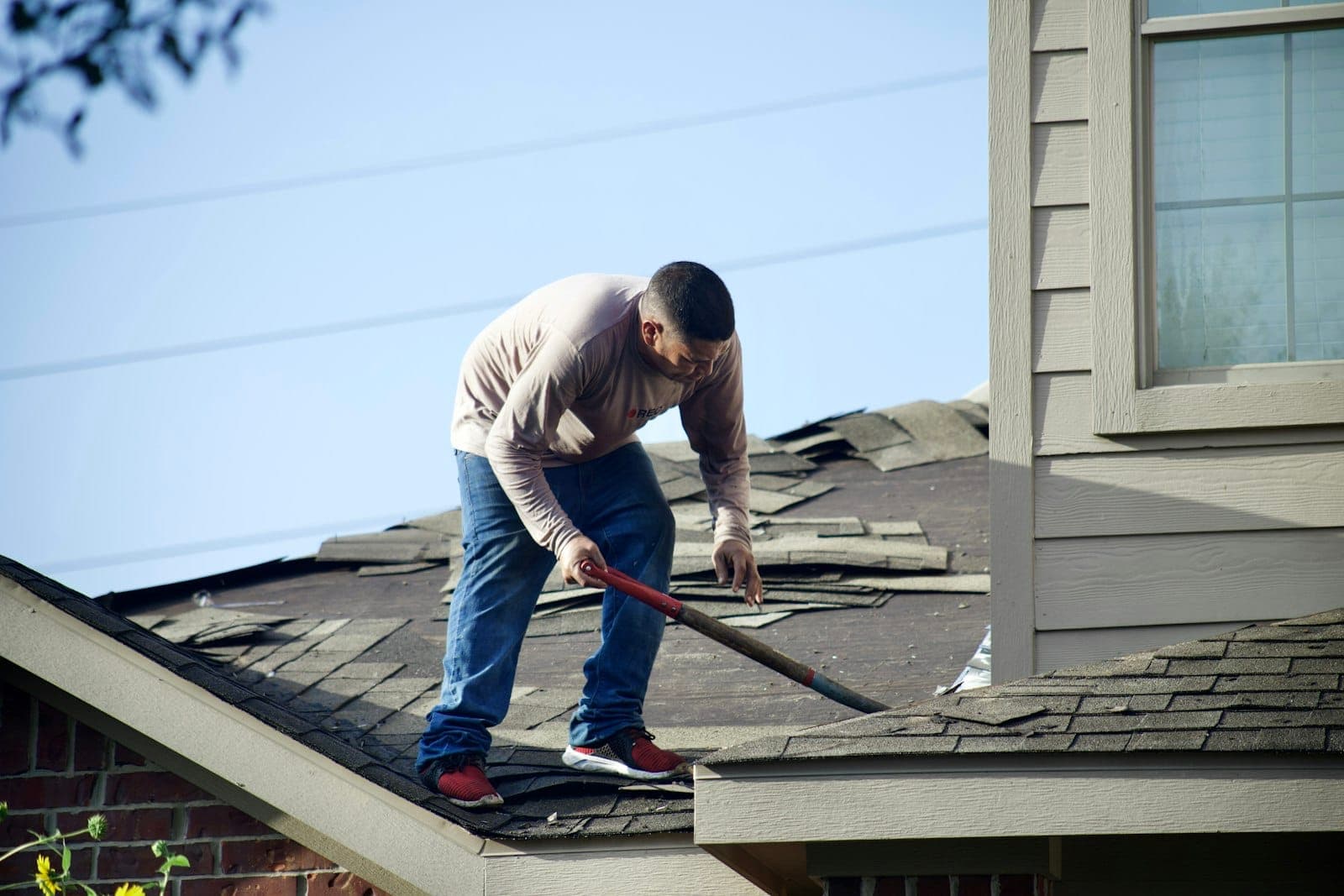 Contractor removing worn shingles during a roof repair
